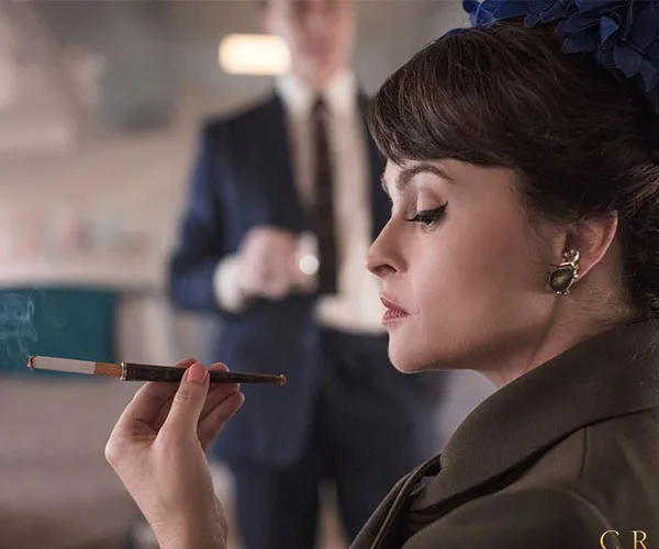 Helena Bonham Carter as Princess Margaret in "The Crown," elegantly holding a cigarette holder with a focused expression.