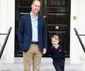 Father and son standing in front of a black door, smiling and holding hands.