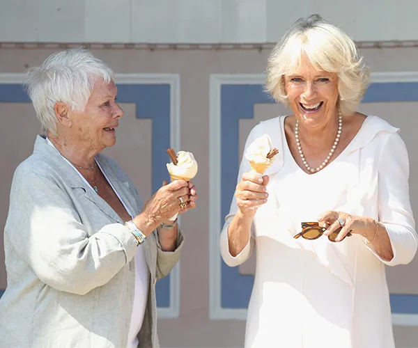 Dame and duchess laughing and holding ice creams, sunny day.
