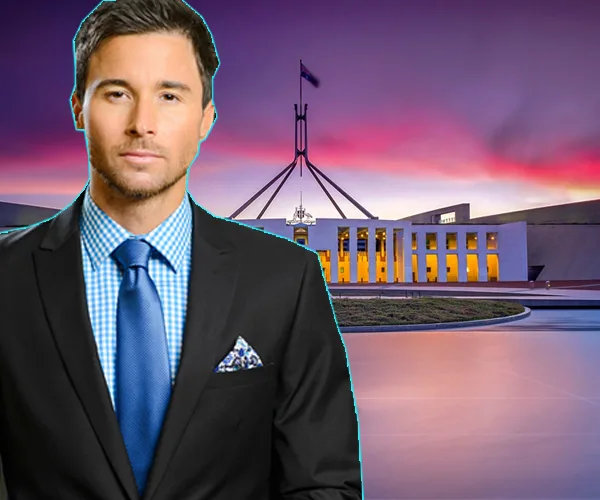 Man in a suit stands in front of the Australian Parliament House at sunset.