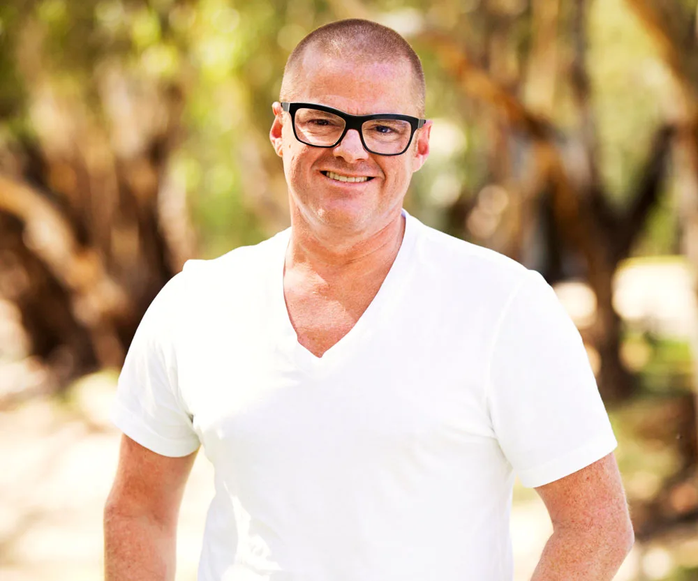 Man in glasses and white shirt smiling outdoors.