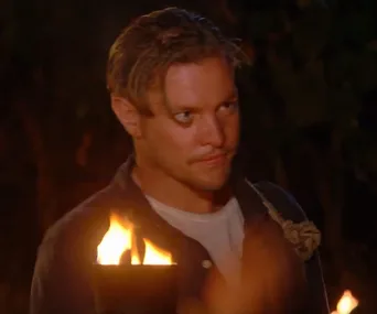 A man holding a torch at night during a Tribal Council on "Survivor Australia."