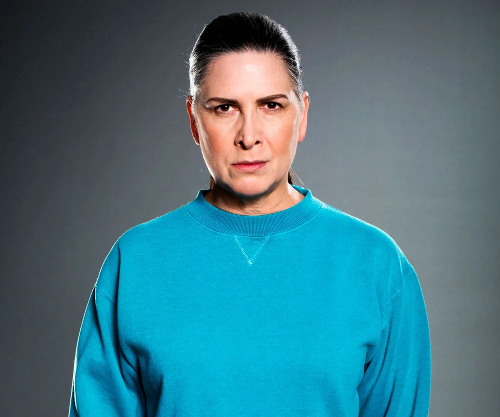 "Character in blue sweatshirt with serious expression against a gray background."