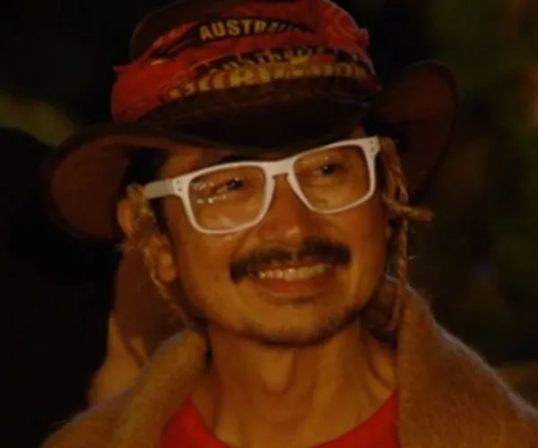 An individual wearing a hat and white glasses, smiling on "Australian Survivor" episode 4.