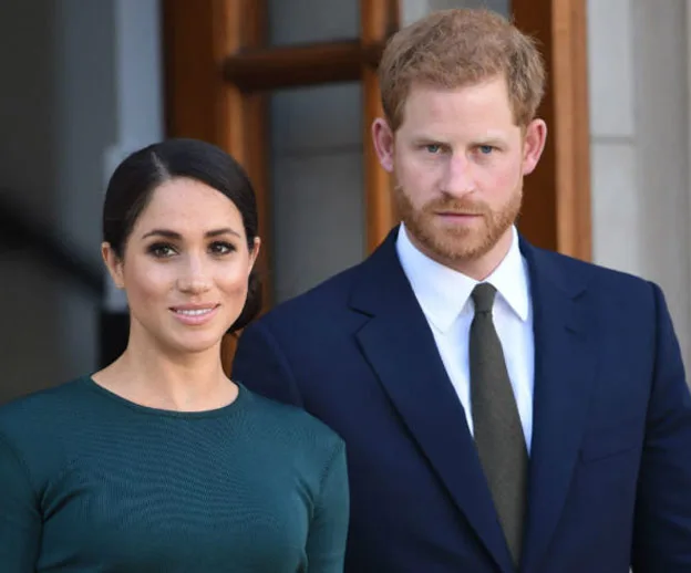 Prince Harry and Meghan Markle standing together outside, dressed in formal attire.