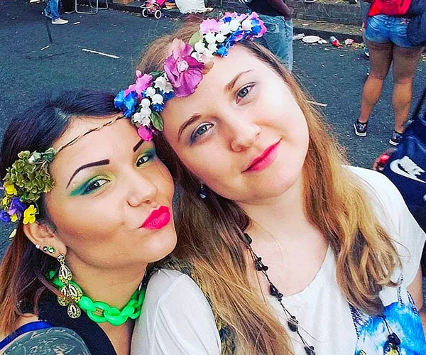 Two women with floral headbands smiling outdoors at a festival.