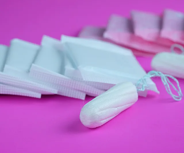 Tampons and sanitary pads on a pink background.