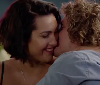 A couple shares an intimate moment, smiling close to each other, appearing affectionate and happy.