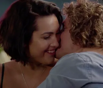 A couple shares an intimate moment, smiling close to each other, appearing affectionate and happy.