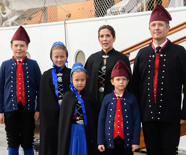 Danish royal family wearing traditional costumes, standing on a ship's deck.