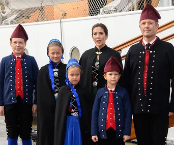 Danish royal family wearing traditional costumes, standing on a ship's deck.