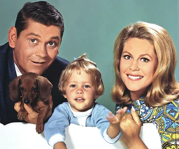 Man, woman, and child with a dog pose cheerfully in a classic setting.