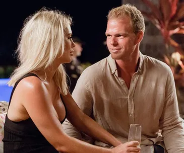 Couple sitting together gazing at each other with drinks in hand.