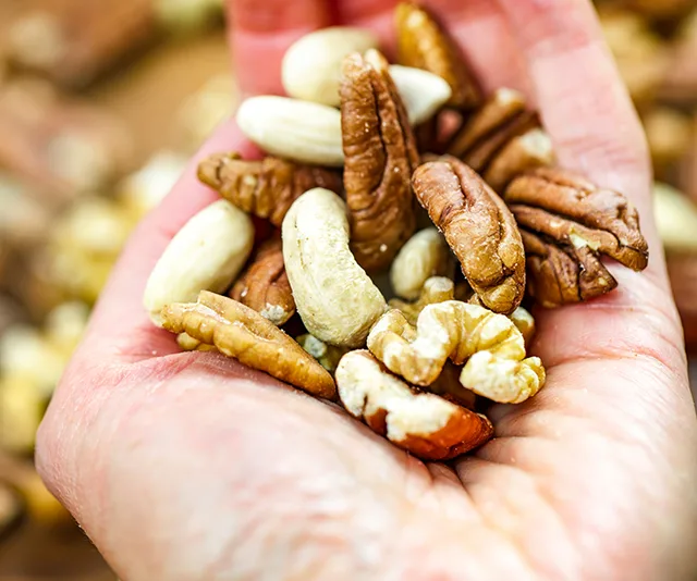 A handful of mixed nuts, including pecans, cashews, and walnuts.