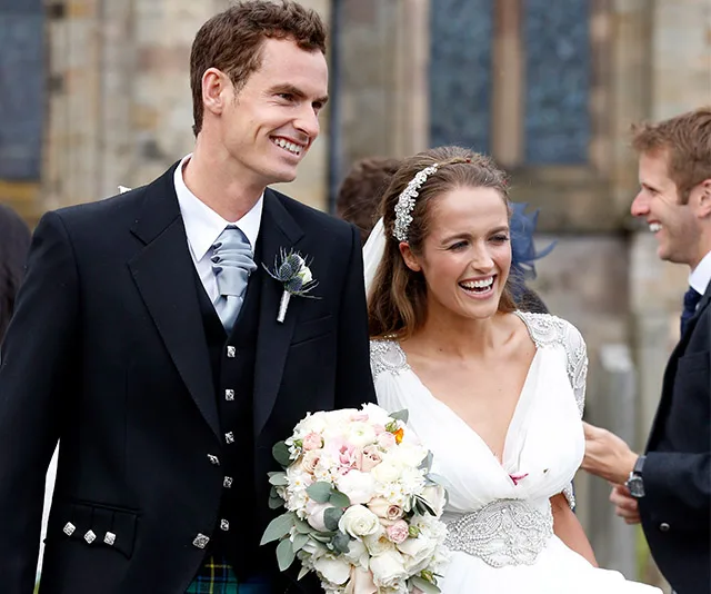 Bride and groom smiling outdoors, bride holding a bouquet.