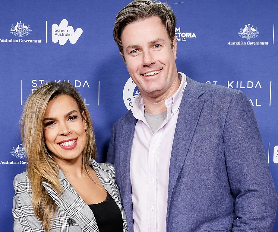 Two people smiling at the St Kilda Film Festival event, standing against a blue promotional backdrop.