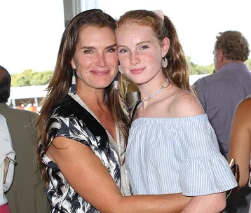 Two women smiling and embracing each other at an outdoor event.