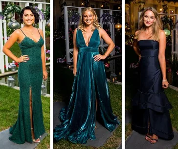 Three women in elegant formal gowns at an outdoor event, standing on grass with floral decor in the background.
