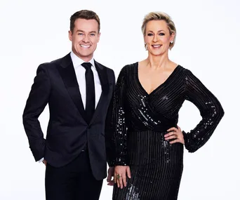 A man and woman in elegant evening attire smile at the camera against a plain white background.