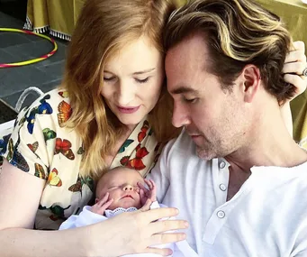 A couple lovingly holds their newborn baby, with both gazing affectionately at the infant.