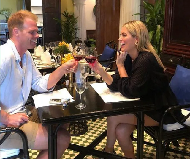 A smiling couple toasting with wine at a restaurant table.