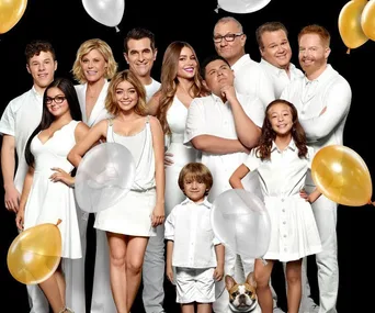 Cast of "Modern Family" in white outfits with balloons, posing against a black background.