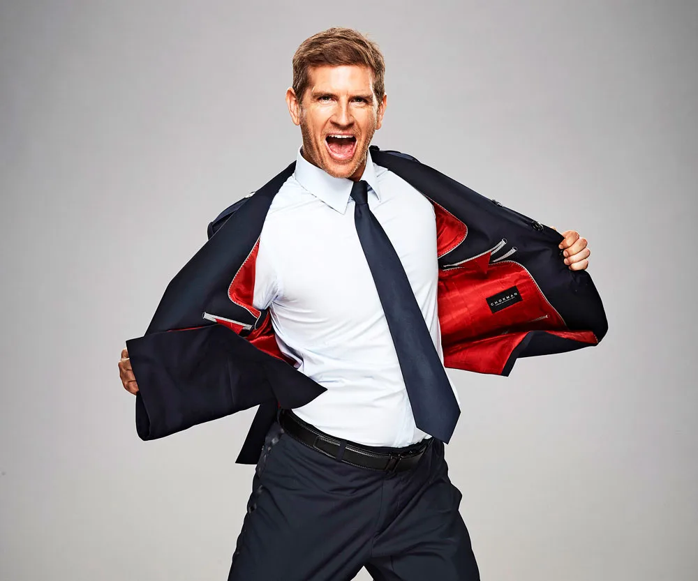 Man in a suit with red lining, energetically pulling it open, expressing excitement.