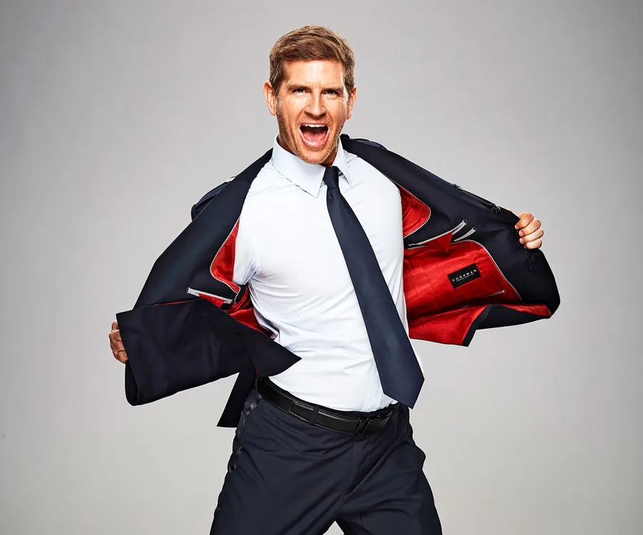 Man in a suit with red lining, energetically pulling it open, expressing excitement.