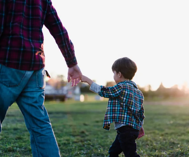 Small boy being led away by adult male.