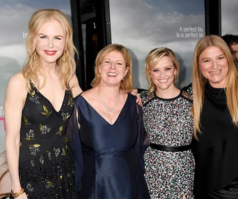 "Cast of 'Big Little Lies' posing together at event, with a poster in the background displaying the show's tagline."