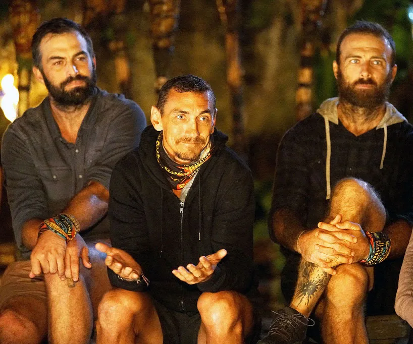 Three contestants sitting at Tribal Council on Australian Survivor, one gesturing with his hands.