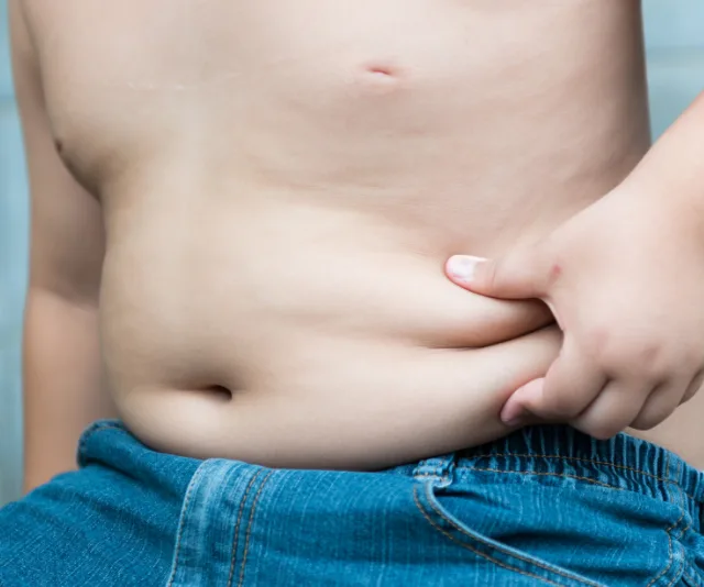 Small boy pinching stomach rolls