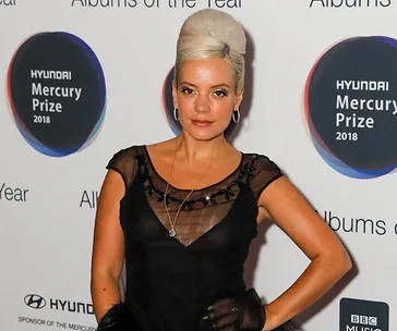 Singer at the Hyundai Mercury Prize 2018, wearing a black dress and standing in front of event backdrop.