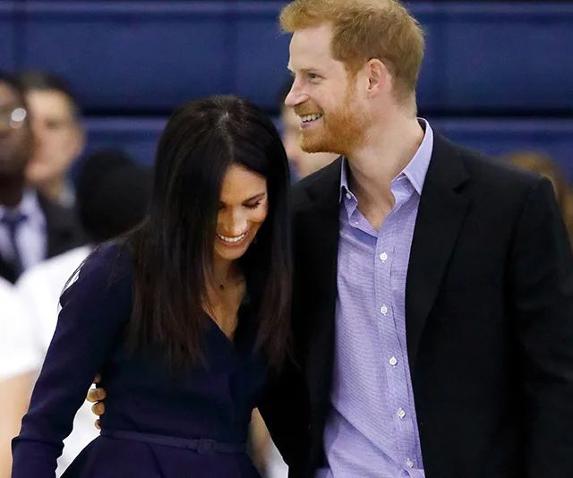 Meghan Markle and Prince Harry smiling and embracing at an indoor event.
