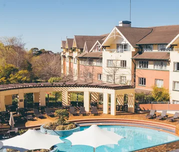 A resort with a pool, sun umbrellas, and a large building under a clear blue sky, ideal for family holidays.