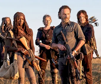 Group of armed survivors standing in a field, characters from "The Walking Dead" series.