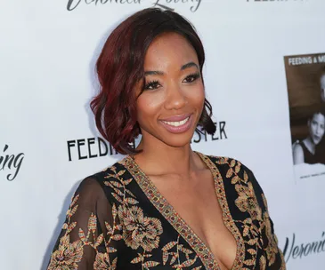A person smiling at an event, wearing a detailed floral dress.