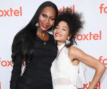 Two individuals smiling in front of a Foxtel backdrop at the Pose Australia event.
