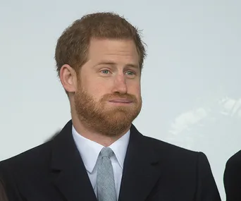 Prince Harry with a surprised expression, wearing a suit and tie.