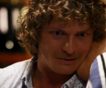 Close-up of a man with curly hair and a mustache in an emotional moment from "Bachelor Australia 2018" finale.