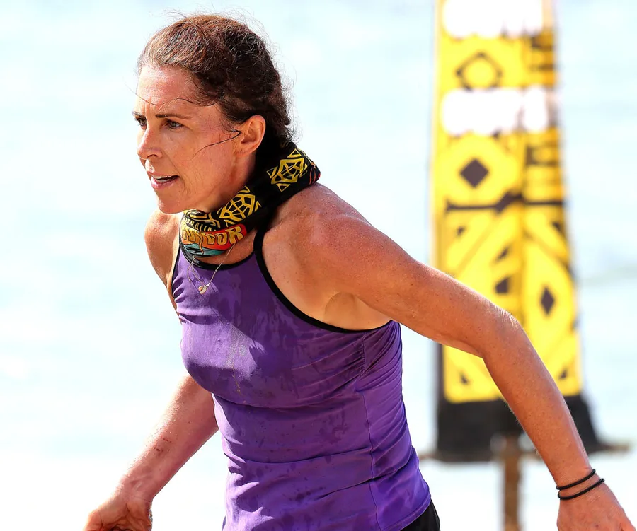 Contestant in purple tank top and tribal buff, running during an outdoor challenge on Australian Survivor.