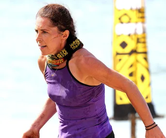 Contestant in purple tank top and tribal buff, running during an outdoor challenge on Australian Survivor.