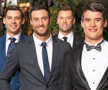 Four men in suits smiling, standing outdoors.