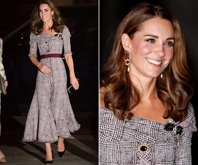 Kate Middleton wearing a plaid dress with a burgundy belt, smiling and walking at a formal event.