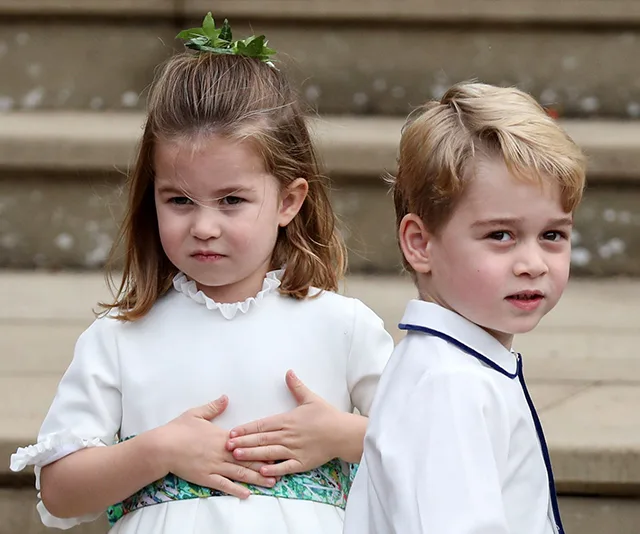Two young children in formal attire, standing on steps at a wedding, with the girl looking serious and the boy smiling slightly.
