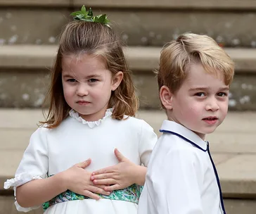 Two young children in formal attire, standing on steps at a wedding, with the girl looking serious and the boy smiling slightly.