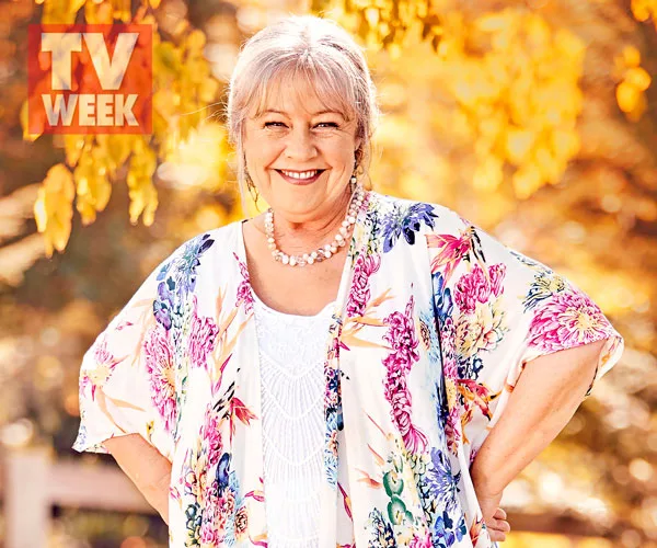 Noni Hazlehurst smiling outdoors, wearing a colorful floral top, with a TV Week logo in the corner.
