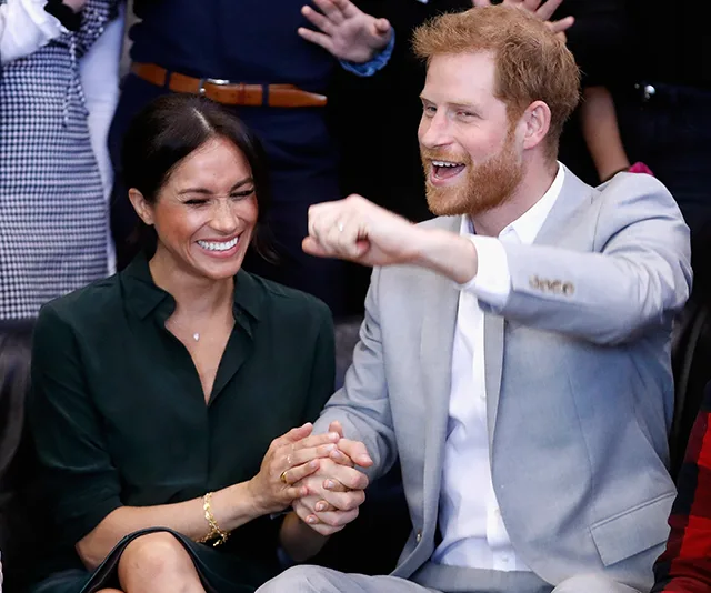 Couple sitting together, holding hands, smiling and appearing joyful during an event.