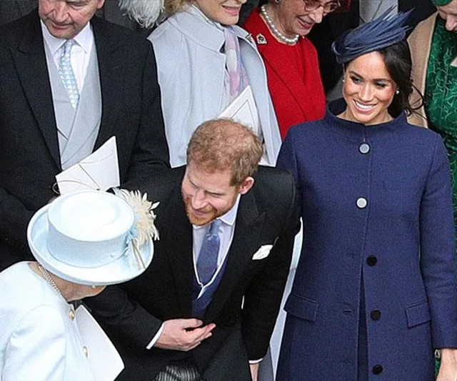 Royal family gathering, with Meghan Markle smiling and Prince Harry bowing to an elderly woman in white.