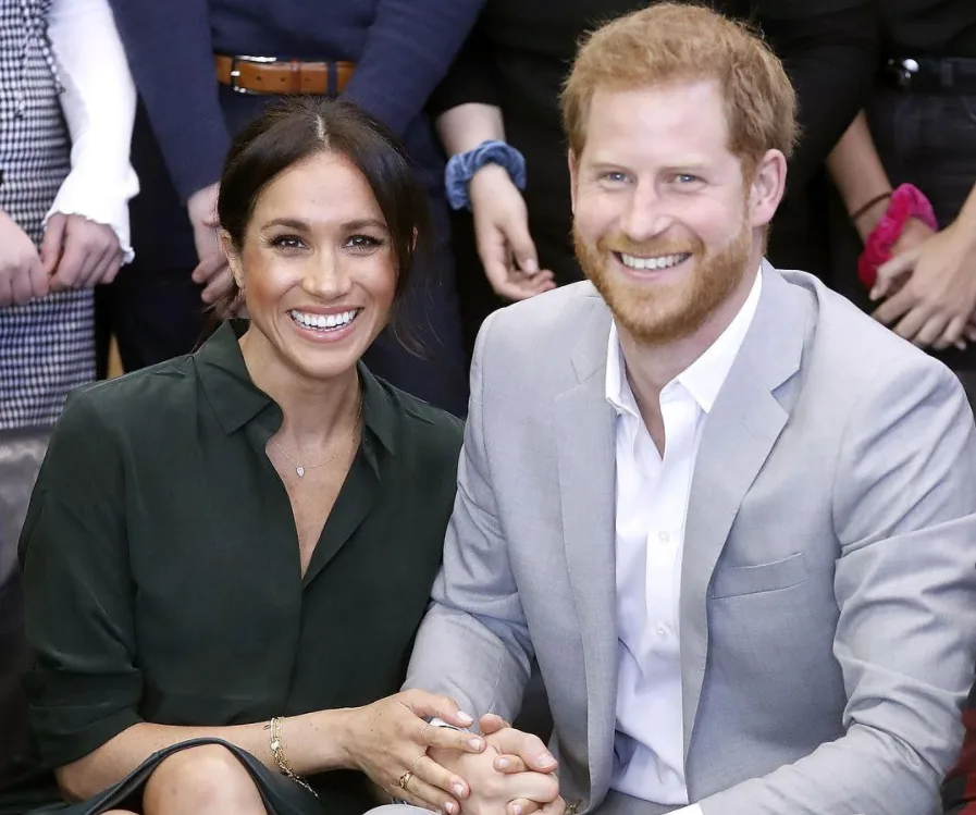 Couple smiling, seated together, the woman wearing a dark top and the man in a light suit.